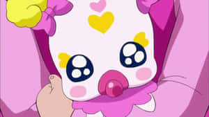 Un baby anime rosa e giallo con cuori e ciuccio in mano.