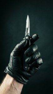 Spent scene av hanskeholdt switchblade, thriller-stemning.