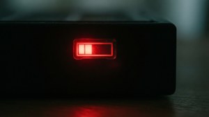 Et mørkt rum med en glødende rød lav batteri-indikator fra en enhed.