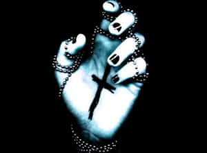 A hand with black nail polish and beaded chains holding a cross against a black background. — Gothic Computer Picture