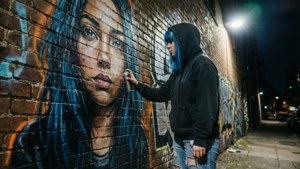 Scène d'art urbain de rue de ViciNeko peignant une fresque murale la nuit