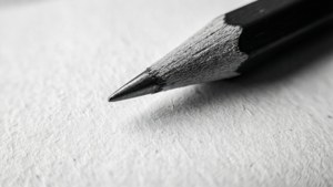 A detailed macro shot of a pencil tip on textured paper in monochrome.