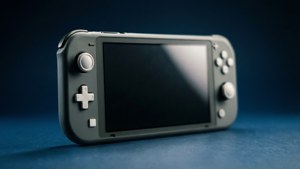 Een dramatisch zijprofiel van een grijze Switch Lite op een donkerblauwe achtergrond.