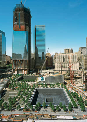 One World Trade Center in costruzione con piscine del Memoriale dell'11 settembre e paesaggio urbano circostante.