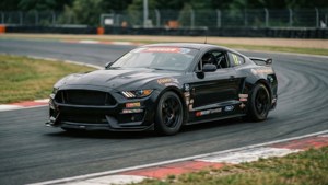 Black Mustang GTD tearing through a racetrack corner