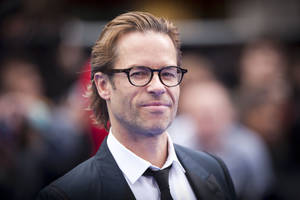 Man in suit and glasses smiling at camera at event. — Guy Pearce Picture
