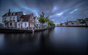 Niederländische Kanalhäuser leuchten in der Dämmerung mit gestreiftem Himmel und ruhiger Wasserreflexion. — Haarlem Wallpaper