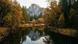 Half Dome mountain reflected in a calm autumn lake surrounded by colorful trees. — USA Wallpaper