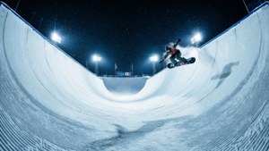 Snowboarder, der in eine beleuchtete Halfpipe unter dem Nachthimmel fährt