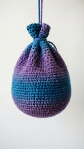 Minimalistisk virkad hacky sack med blå-lila gradient hängande på vitt.