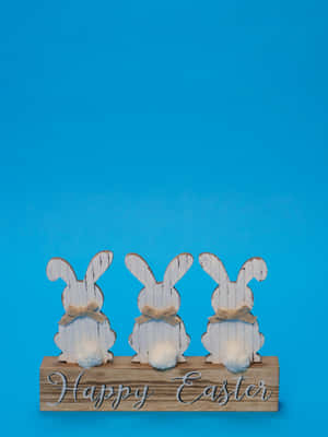 Three wooden Easter bunnies with twine bows on a 'Happy Easter' sign against blue. — Cute Happy Easter Picture