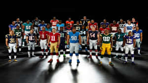 NFL football players in team uniforms posing on a dark stage under spotlights.