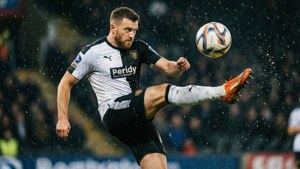 Kamil Jozwiak kopt de bal in de regen