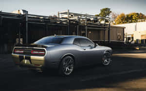 Silberner Muscle-Car geparkt in industrieller Umgebung bei Sonnenuntergang. — Dodge Challenger Hintergrundbild
