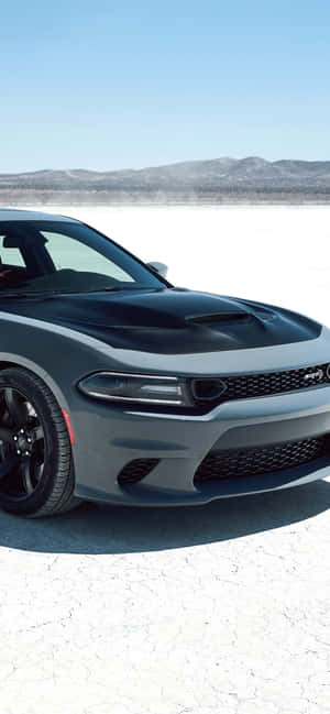 Grauer Dodge Challenger auf rissiger Salzwüste mit Bergen im Hintergrund unter blauem Himmel — Hellcat iPhone Wallpaper