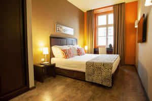 Modern hotel bedroom with orange walls wooden floors and patterned bed linens. — Hotel Room Picture