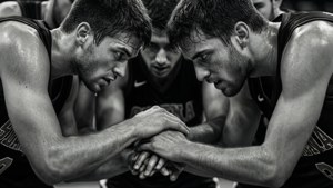 Gambar hitam-putih yang kasar dari pemain basket dalam huddle sebelum pertandingan.