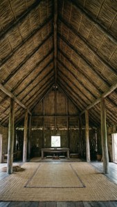 Innenansicht eines traditionellen kiribatischen Maneaba-Versammlungshauses mit Strohdach und gewebten Matten.