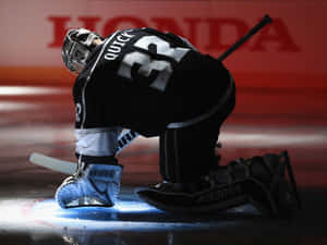 Hockey goalie kneeling on ice during game with red Honda background.