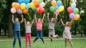 Des enfants heureux sautant avec des ballons colorés dans un parc.