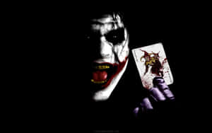 Joker tenant une carte joker tachée de sang avec un sourire sinistre.