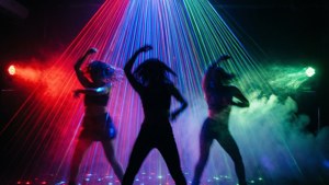Ballerini energici sotto raggi laser colorati con motion blur.