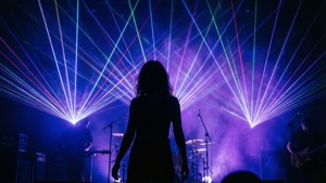 Uma silhueta dramática com padrões geométricos de laser e atmosfera esfumaçada em um show.