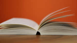 Open book with white pages on wooden surface against orange background — Knowledge Picture