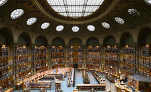 Circular grand library with high arched ceilings and rows of bookshelves. — Library Wallpaper