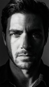 Retrato en blanco y negro de alto contraste de Yair Rodríguez con medio rostro sombreado.