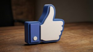 Realistinen 3D-taustakuva Facebookin tykkäys-peukusta puisella pöydällä.