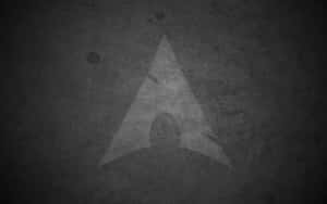 Ein dreieckiges Logo auf einer rauen, dunklen Wand mit Struktur und Abnutzung. — Linux Desktop Hintergrundbild