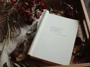 Offenes Buch mit Shakespeare-Zitat umgeben von getrockneten Rosen und Baumwolle in einem Holztablett. — Book Quotes Wallpaper