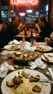 A candid messy restaurant table after a lively meal with neon reflections.
