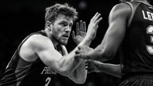 Foto em preto e branco de Payton Pritchard em uma postura defensiva, intensa e dramática.