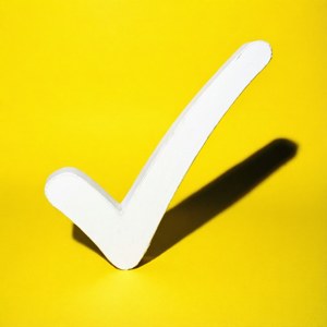 Marca de verificação branca com sombra longa em fundo amarelo.