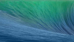 A towering ocean wave curls into a perfect barrel with green and blue hues. — Black Mac Picture