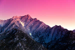 Pink and purple twilight over a rugged mountain range with snow patches. — Black Mac Picture