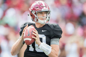 Football quarterback in Alabama uniform holding ball during game. — Mac Jones Picture