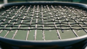 En makro nærbilde av padel racket strenger med fuktperler.