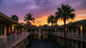 Een levendige zonsondergang boven het Magic Castle motel met kinderen die op het balkon spelen.