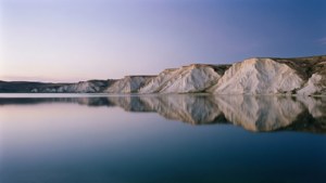Un paysage crépusculaire serein d'un lac calme reflétant de pâles falaises de calcaire riches en magnésium.