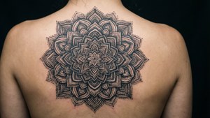 Een symmetrische zwartwerk mandala tattoo gecentreerd op de rug.