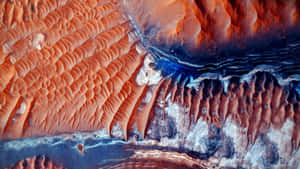 Vibrant orange and blue layered rock formations with intricate ripple textures. — Mars 4K Wallpaper