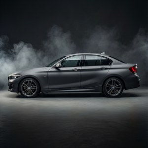 Berlina BMW grigio opaco in studio fumoso con illuminazione drammatica.