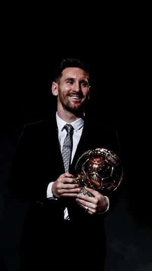 Lionel Messi in a suit holding a golden soccer ball trophy with a bright smile. — Trophy Picture