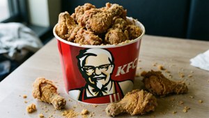 Realistischer unordentlicher KFC-Eimer mit verstreutem Hühnchen, einladend und lässig.