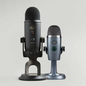 Two Blue brand microphones one black one gray standing on stands against white background
