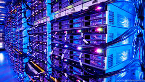 Rows of server racks in a data center with glowing blue and purple lights and cables. — Database Wallpaper