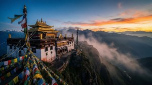 Un tempio buddista tibetano sorge su una vetta montuosa nebbiosa all'alba, con bandiere di preghiera che sventolano.